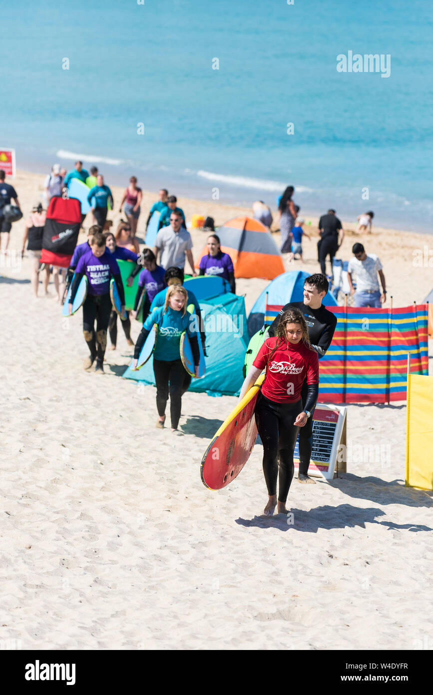Un istruttore di surf da Fistral Beach Surf School portando la sua classe di studenti attraverso Fistral Beach dopo una lezione di surf. Foto Stock