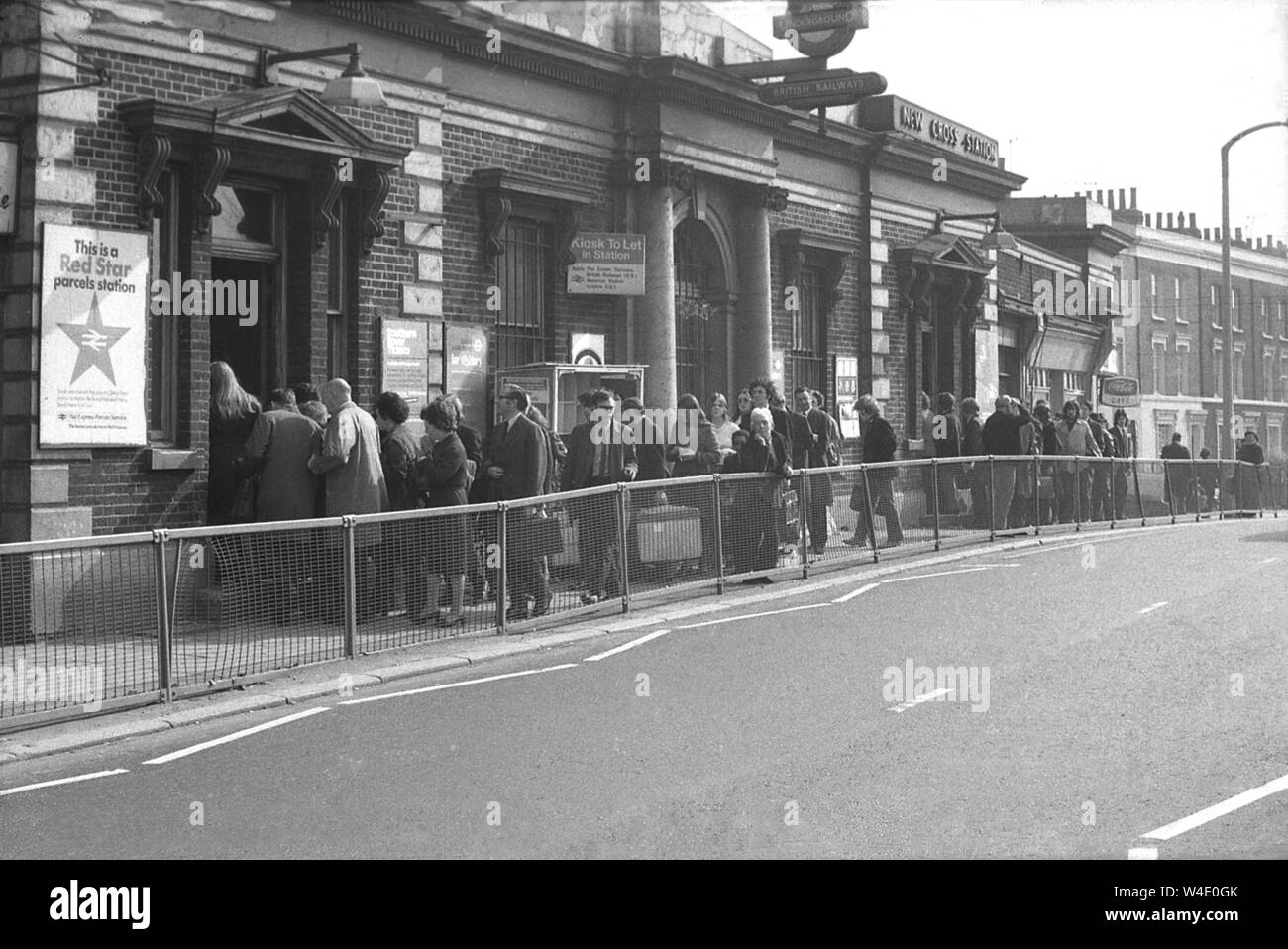 Anni Settanta, storico, persone in coda al di fuori dell'ingresso per il New Cross Station, a sud-est di Londra stazione ferroviaria, probabilmente a causa di una piattaforma di sovraffollamento a causa di una linea ferroviaria di lavoratori in sciopero comune a quei tempi. La stazione inaugurata nel 1850 e post WW2 divenne una parte delle ferrovie britanniche. In questo momento, l'originale stazione victoran edificio sul ponte stradale era ancora in esistenza ma nel decennio successivo è stato sostituito e si è mosso come le piattaforme e le vie sono state demolite e alterato. Foto Stock