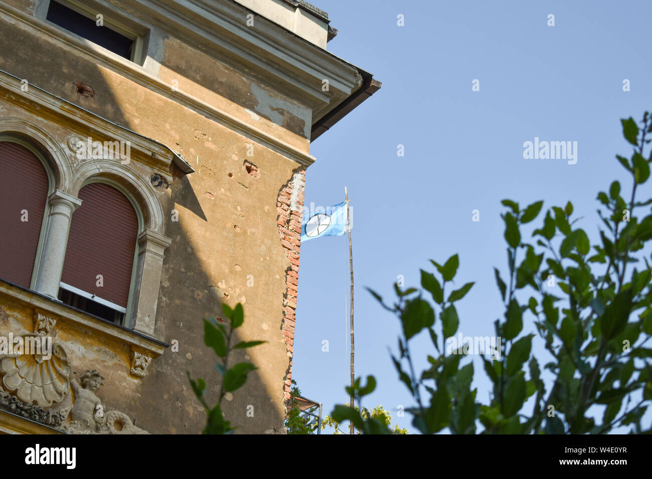 Bandiera con simbolo di pace dietro palazzo storico in Opatija, Croazia Foto Stock