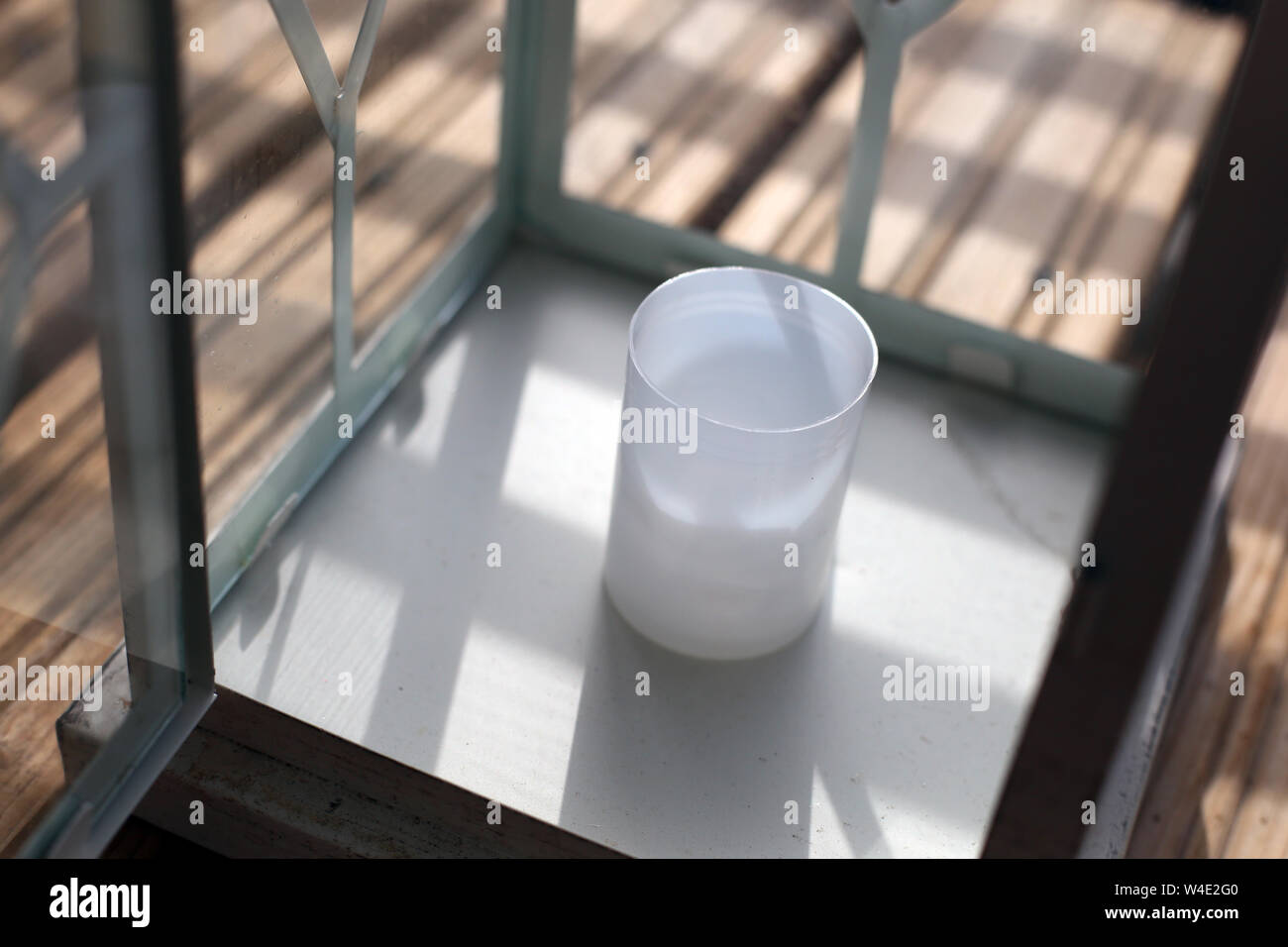 Bianco e Marrone di lanterne su un pavimento di legno durante una giornata di sole. Fotografato in balcone con strisce di recinzione in vetro fare delle belle ombre. Primo piano. Foto Stock