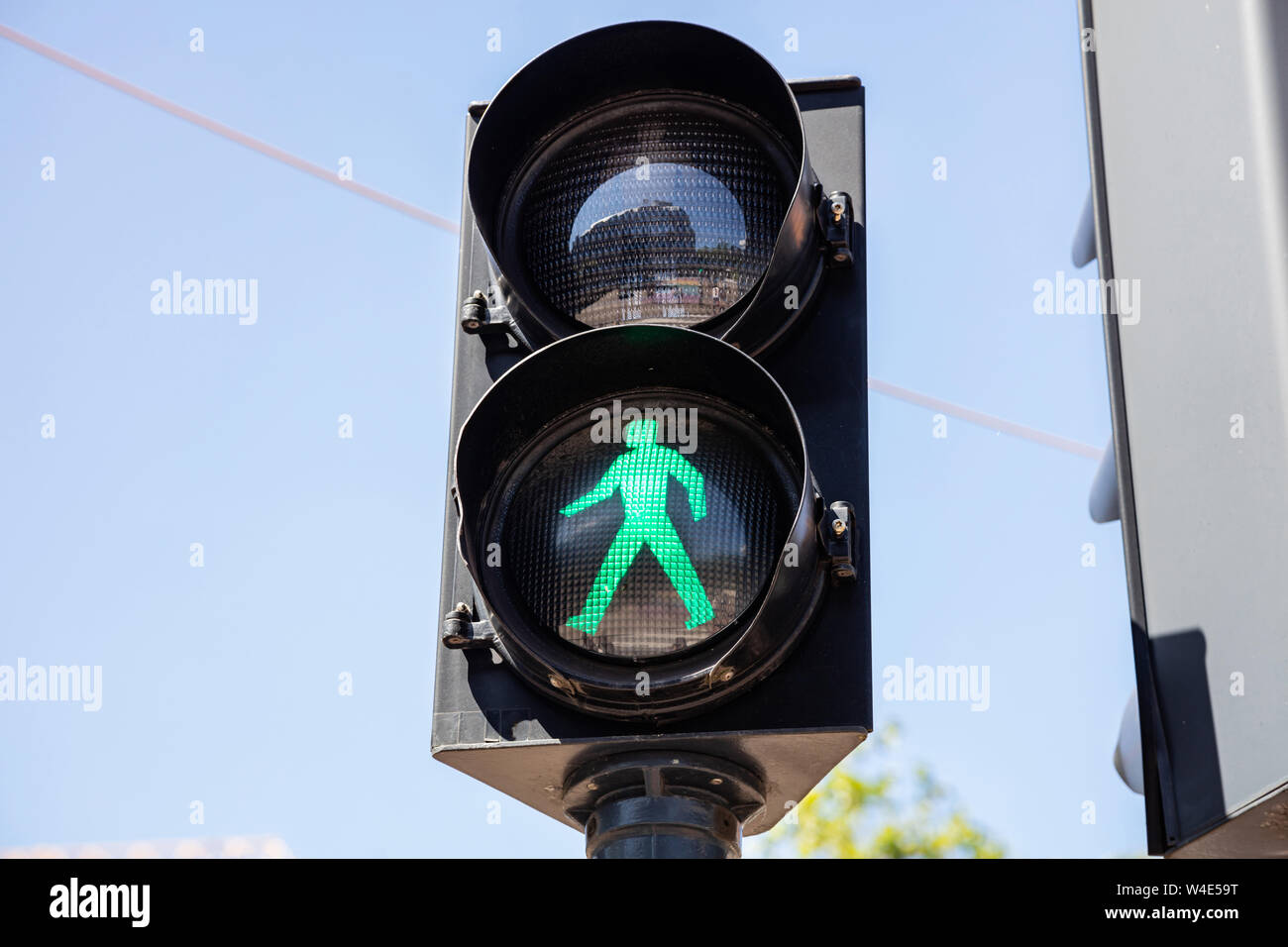 Andare a firmare, semaforo verde per pedoni contro il cielo blu e chiaro dello sfondo. Attraversamento pedonale con sicurezza Foto Stock