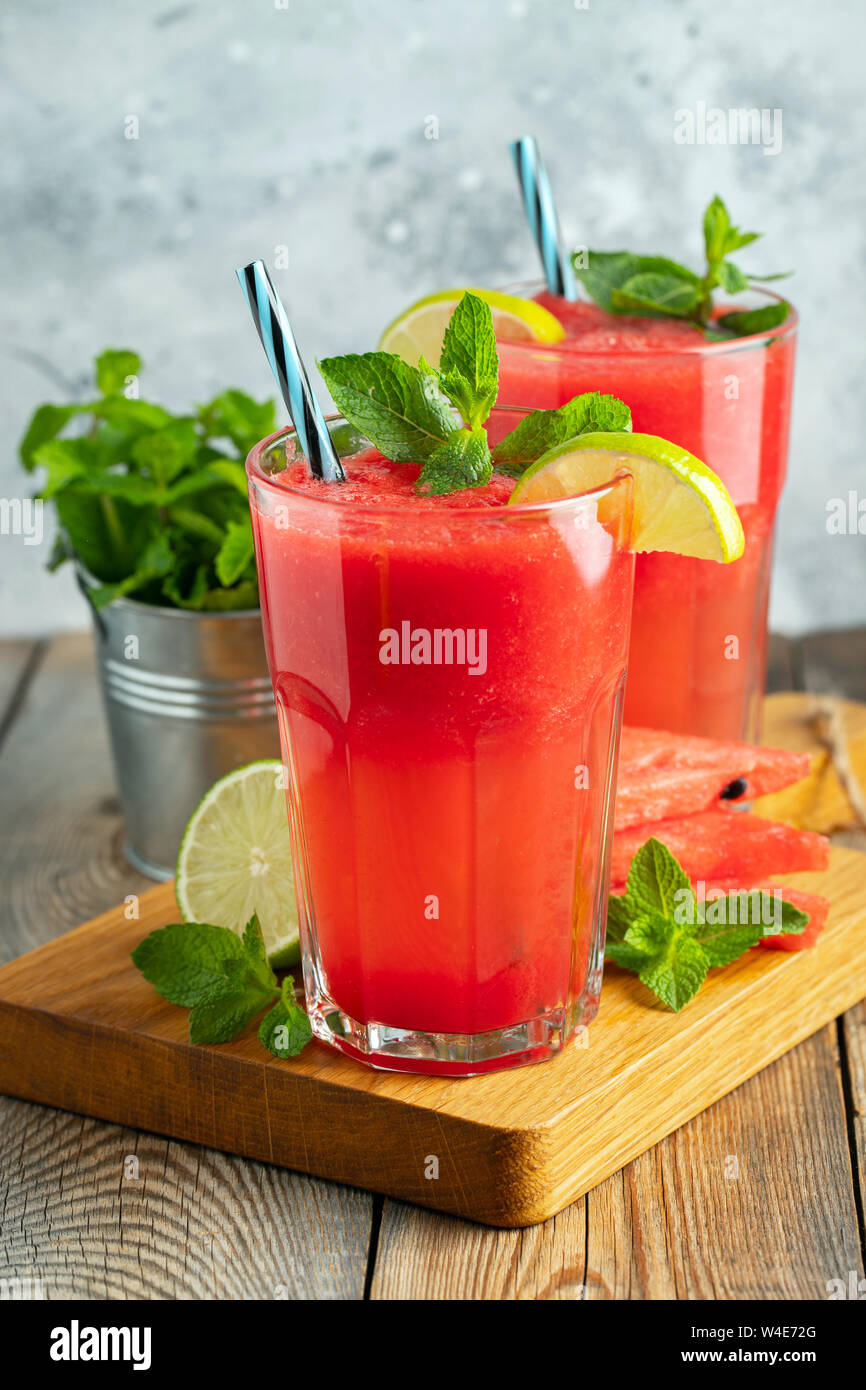 Anguria slushie con lime e menta, estate una bevanda rinfrescante in bicchieri alti su un fondo azzurro. Dolce frullato freddo. Foto Stock