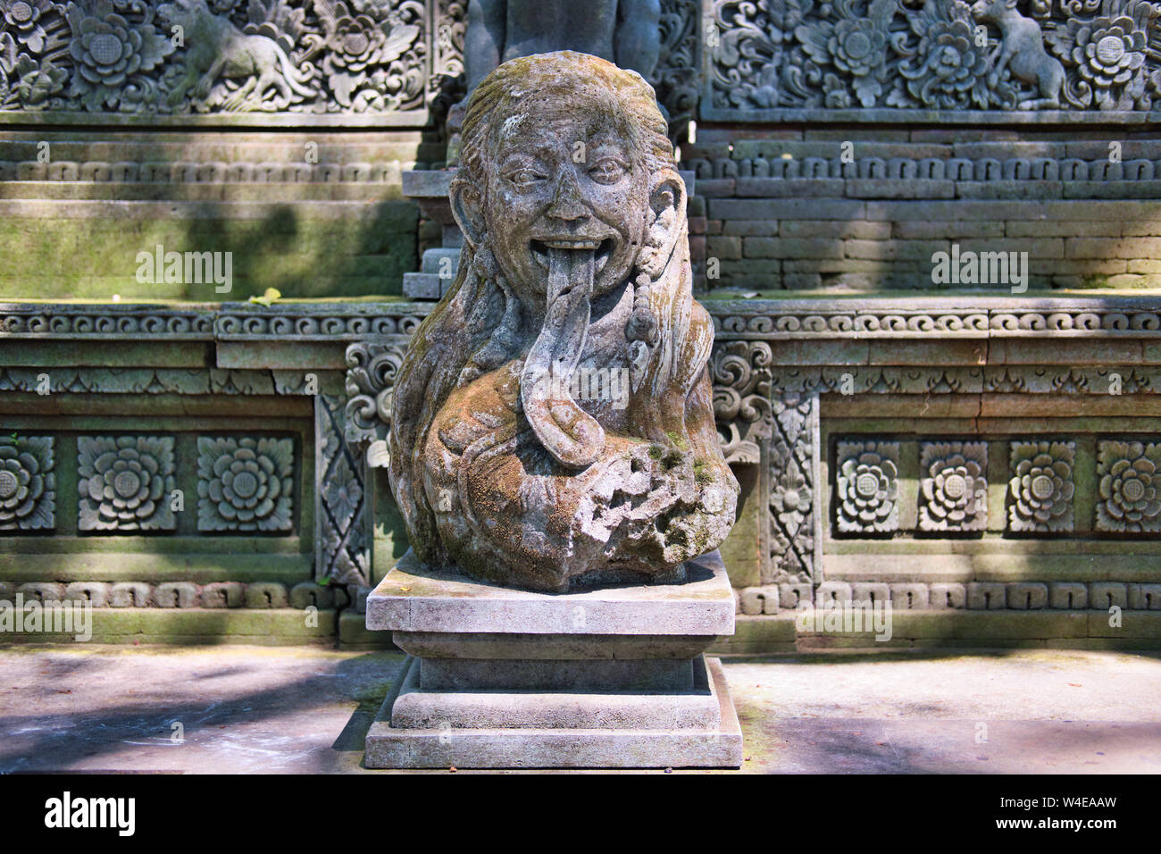 Simpatiche statua di un tempio a Bali isola ricoperta di muffa verdastra in una calda estate. Foto Stock