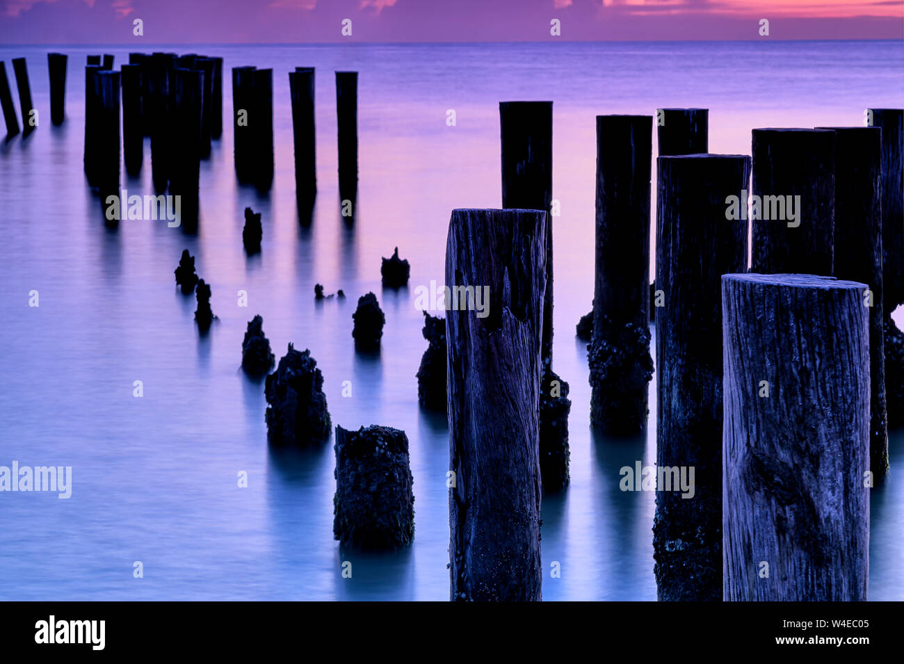 Vecchia Napoli Molo palificazioni stagliano contro il tramonto in Naples, Florida Foto Stock