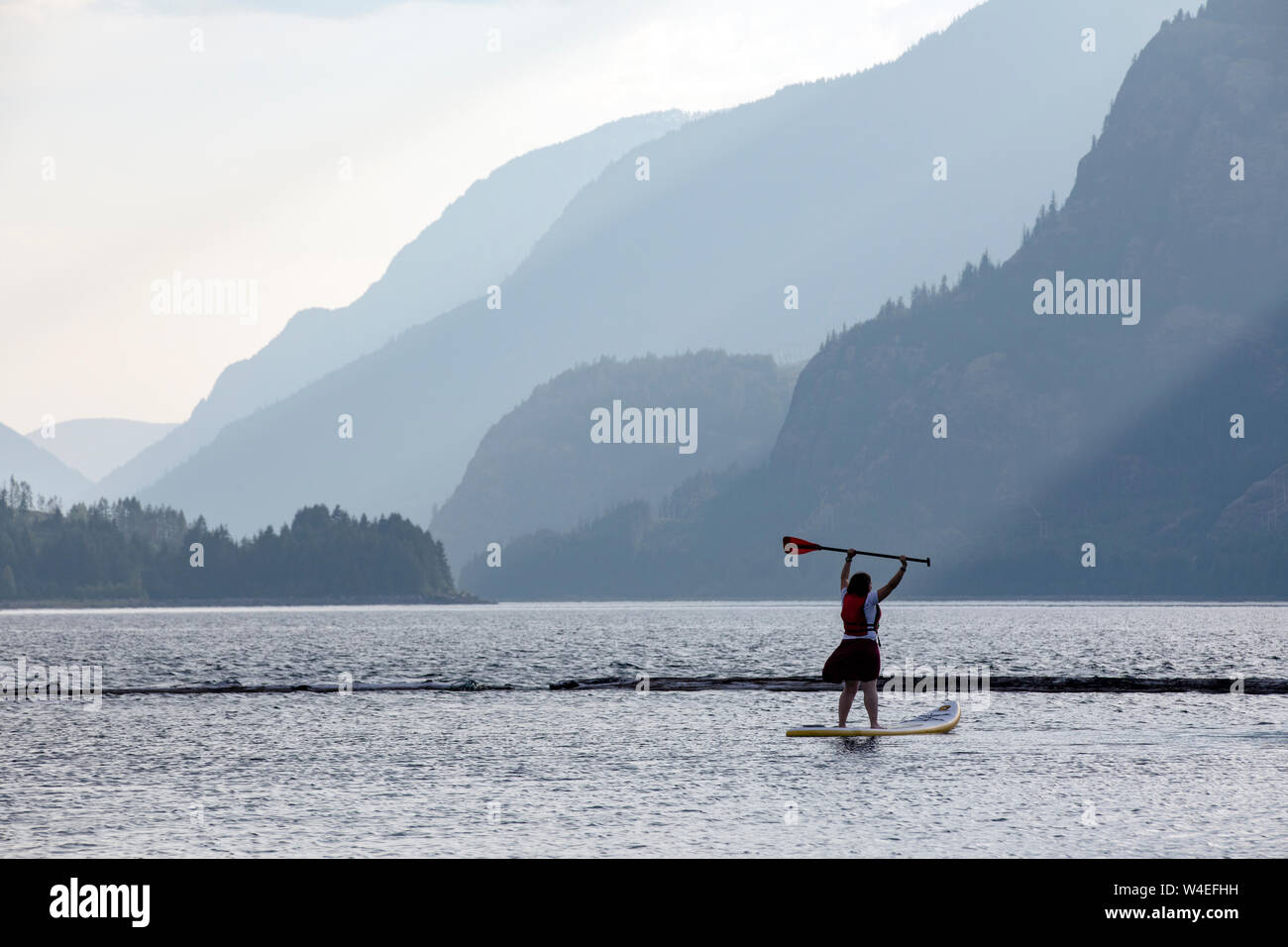 Ragazza giovane stand-up paddleboarding su superiore Campbell lago a Strathcona Park Lodge in Strathcona Provincial Park, vicino a Campbell River, Vancouver Islan Foto Stock
