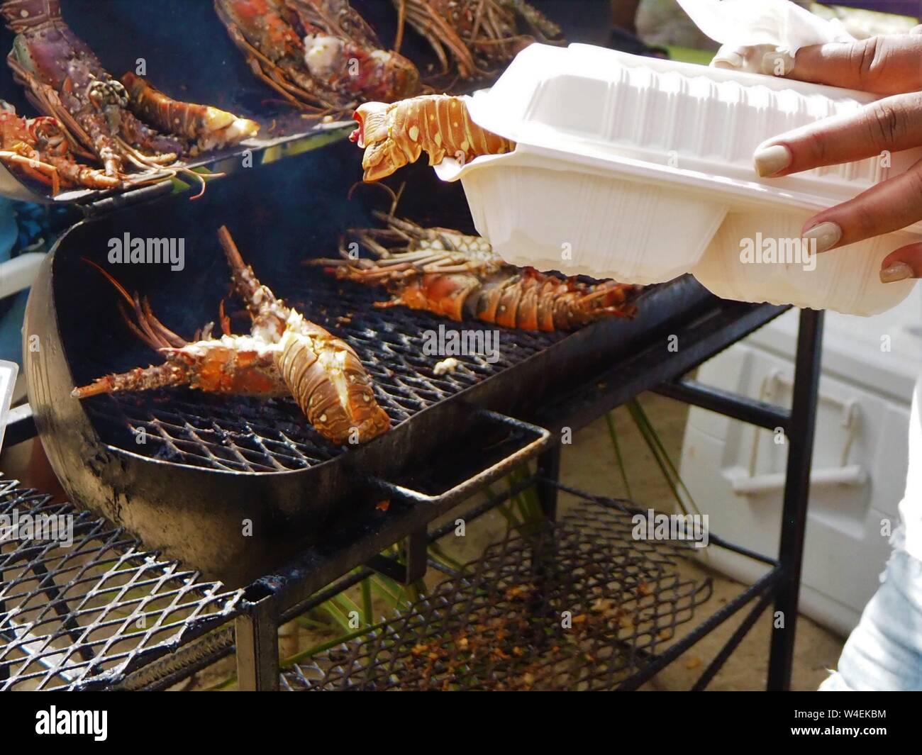 BBQ Placencia aragosta lobster festival, Belize, dei Caraibi. Bar essere Que per prendere il via in contenitore di plastica. barbecue Foto Stock