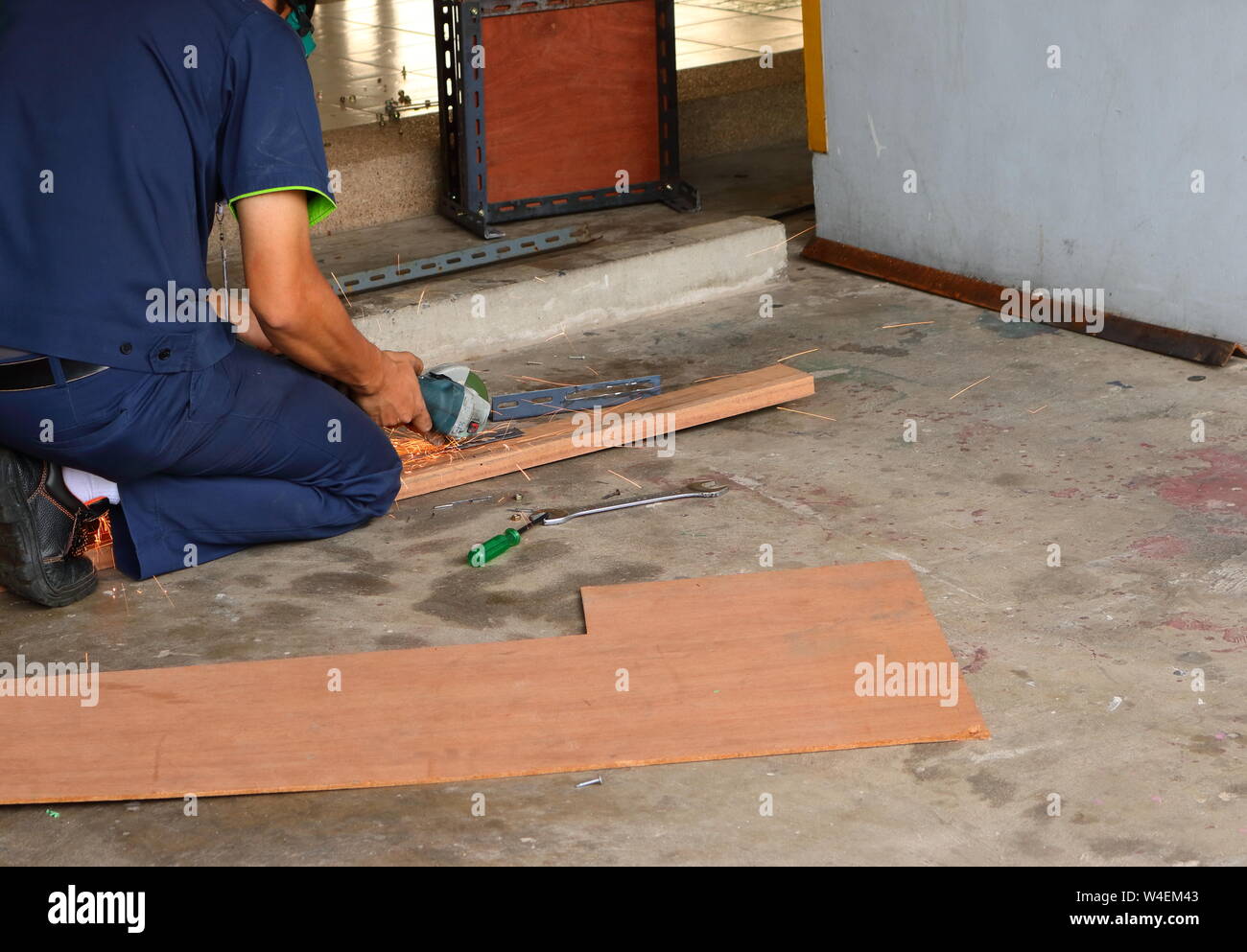 Un lavoratore lavora con un palmare macchina rettificatrice, egli deve concentrarsi sul suo lavoro per la sicurezza Foto Stock