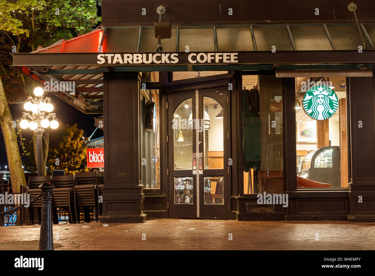Ingresso di Starbucks Coffee shop in Gastown, del centro cittadino di Vancouver, BC incandescente durante la notte. Foto Stock