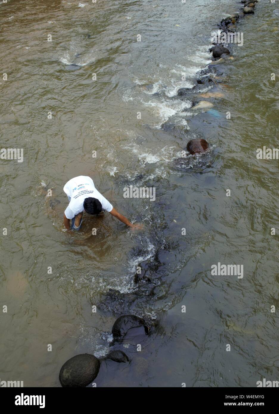 Bogor, West Java, Indonesia - Luglio 2019 : un uomo messo la pietra per la costruzione di una piccola diga nel fiume Ciliwung. Foto Stock Bogor, West Java, Indonesia - Luglio 2019 : un uomo messo la pietra per la costruzione di una piccola diga nel fiume Ciliwung. Foto Stock
