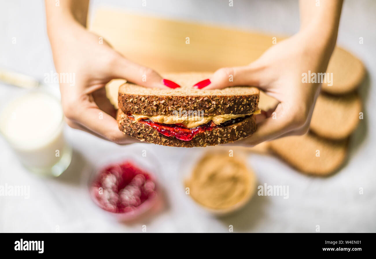 Giovane donna tenendo un burro di arachidi e sandwich di gelatina Foto Stock