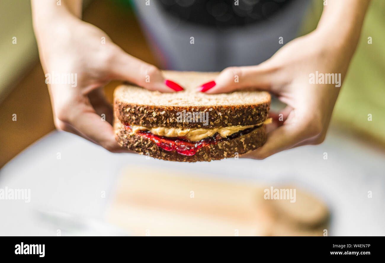 Giovane donna tenendo un burro di arachidi e sandwich di gelatina Foto Stock