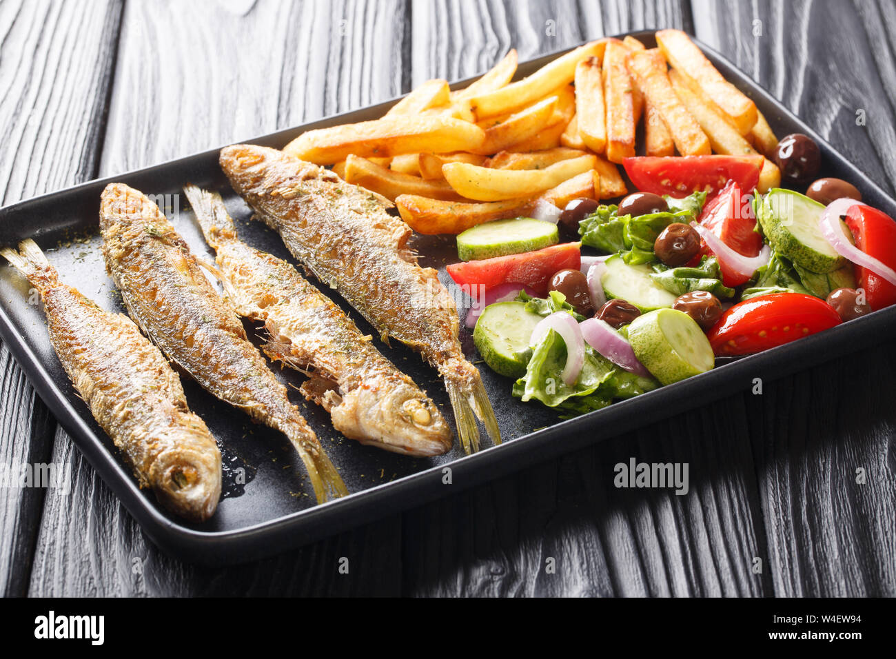 Fresche fritte Boops boops pesce con estate insalata di verdure e patate fritte close-up su una piastra sul tavolo orizzontale. Foto Stock