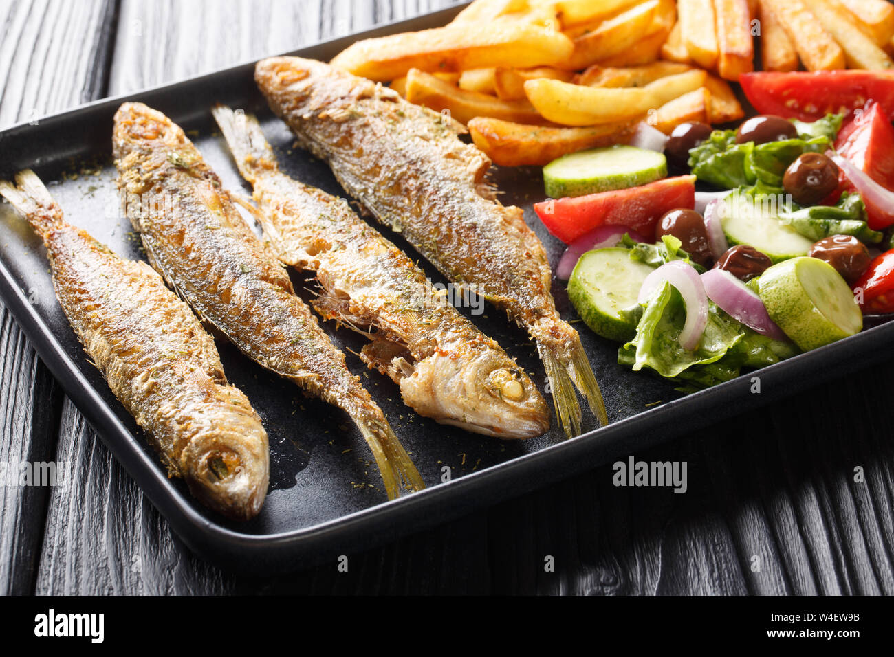Cucina mediterranea Fried Boops boops pesce con verdura fresca insalata e patatine fritte close-up su una piastra sul tavolo orizzontale. Foto Stock