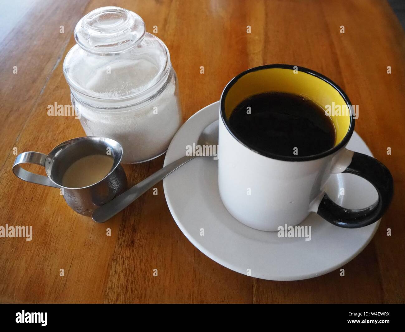 Caffè, panna e zucchero. Cafe con leche. Una grande tazza di caffè con il latte e lo zucchero con un cucchiaio. Foto Stock