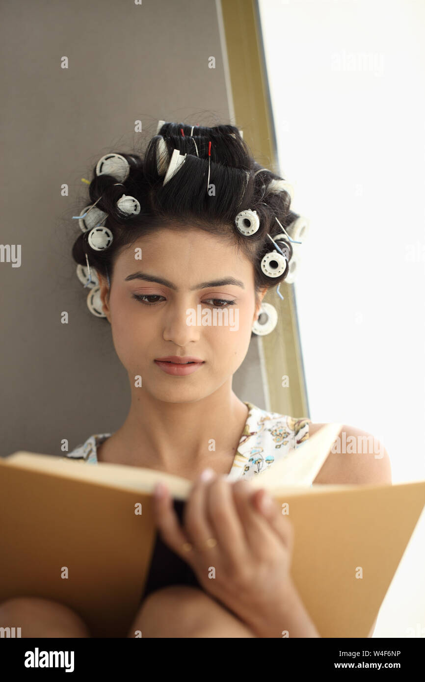 Indian giovane donna la lettura di un libro a casa Foto Stock