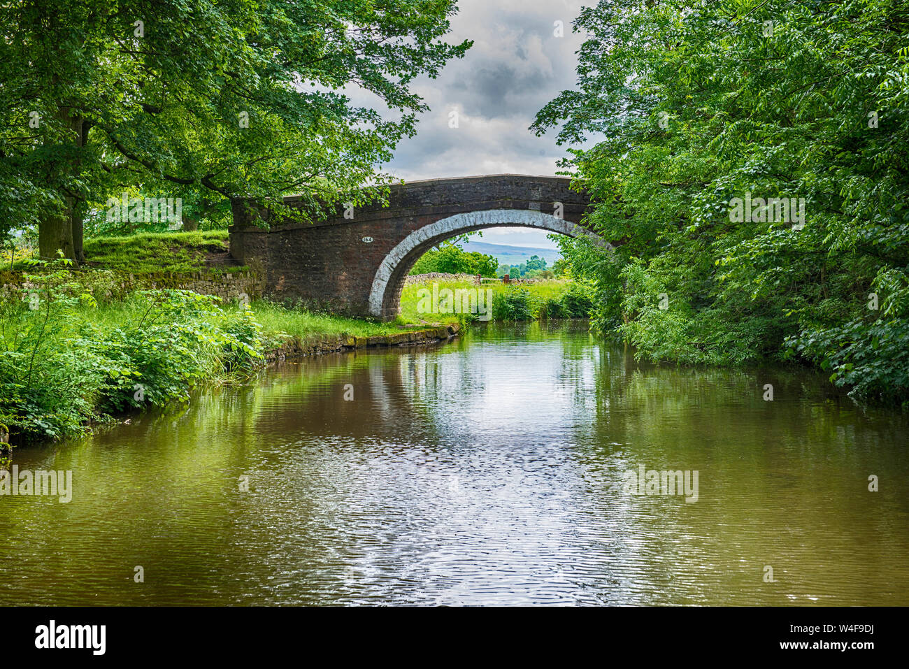 Vista di un inglese un paesaggio rurale paesaggi sulla British canale navigabile durante il giorno nuvoloso con old stone road bridge Foto Stock