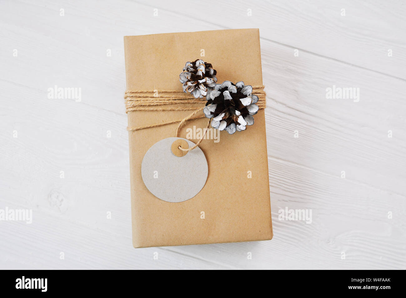 Kraft regalo di Natale scatola con corda, mockup tag, rocche su sfondo bianco. Close up vista superiore Foto Stock