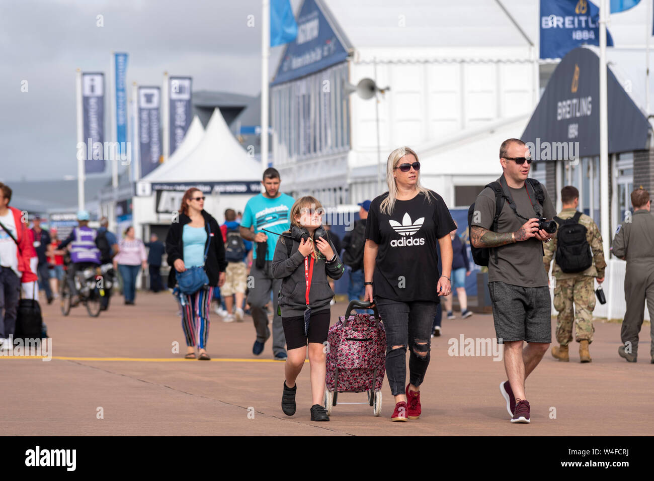 Famiglia in folla al Royal International Air Tattoo airshow, RAF Fairford, Cotswolds, UK. Ragazza giovane, femmina, con cuffie radio con i genitori a piedi Foto Stock