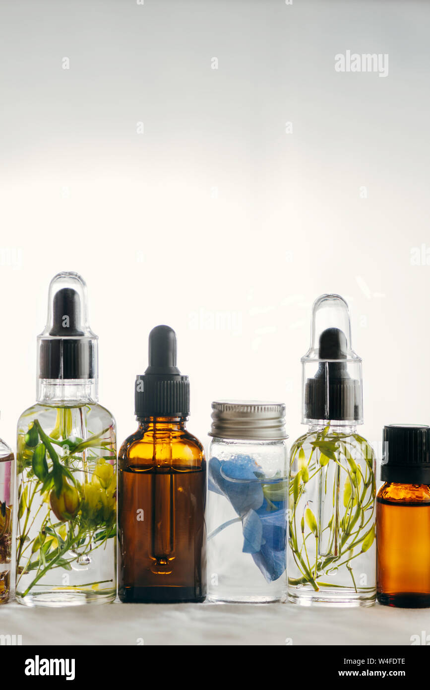 Bottiglie trasparenti di olio essenziale con erbe aromatiche e fiori, un trattamento naturale per massaggi, aromaterapia o spa. Le medicine naturali Foto Stock