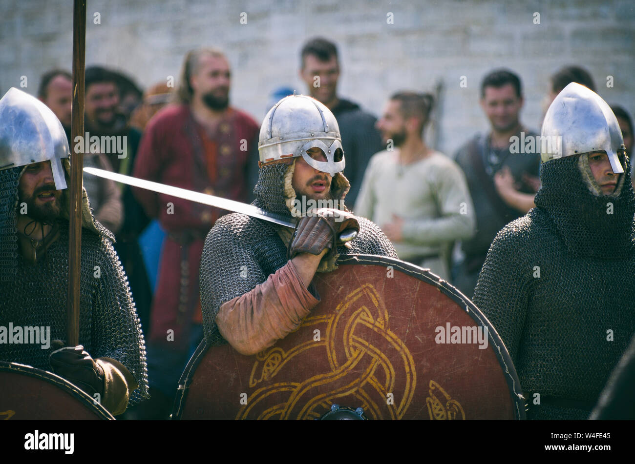 Staraya Ladoga, San Pietroburgo, Russia - 22 Giugno 2019: Viking in mail a catena e con una visiera che tiene una spada sulla sua spalla tra due guerrieri Foto Stock