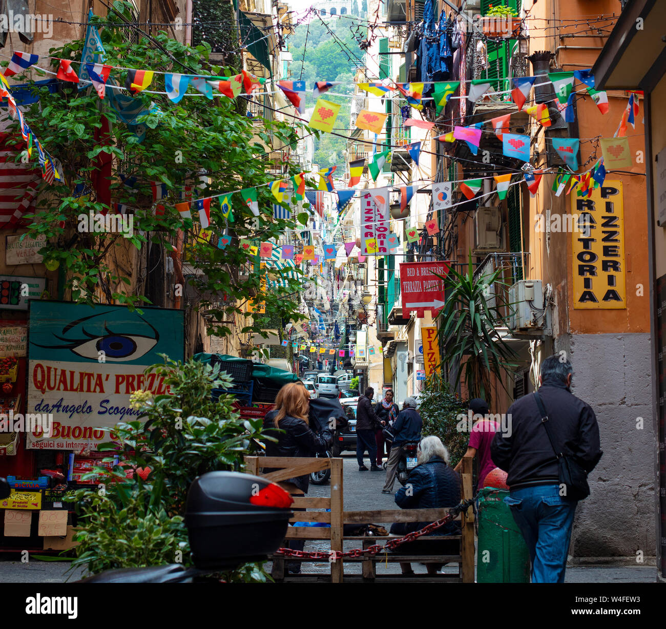 Una strada nel quartiere spagnolo di napoli, Italia, decorata con bandiere e pavese in più colori e la gente del luogo passeggiando attraverso. Foto Stock