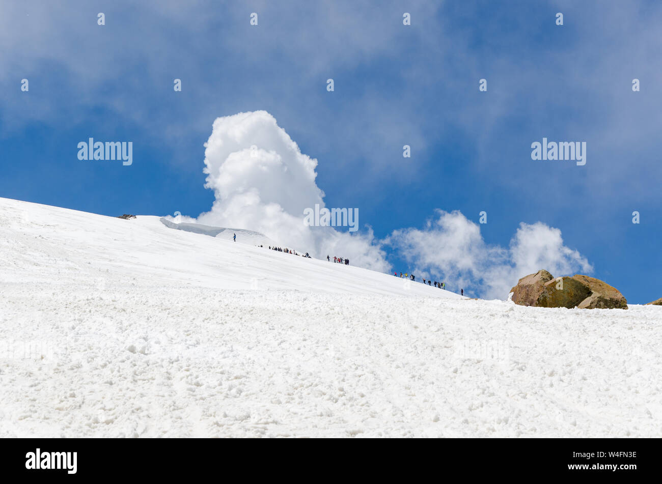 Piccole figure di esseri umani camminare lontano nel bianco della neve paesaggio riempito a picco Apharwat, Gulmarg, Jammu e Kashmir India Foto Stock