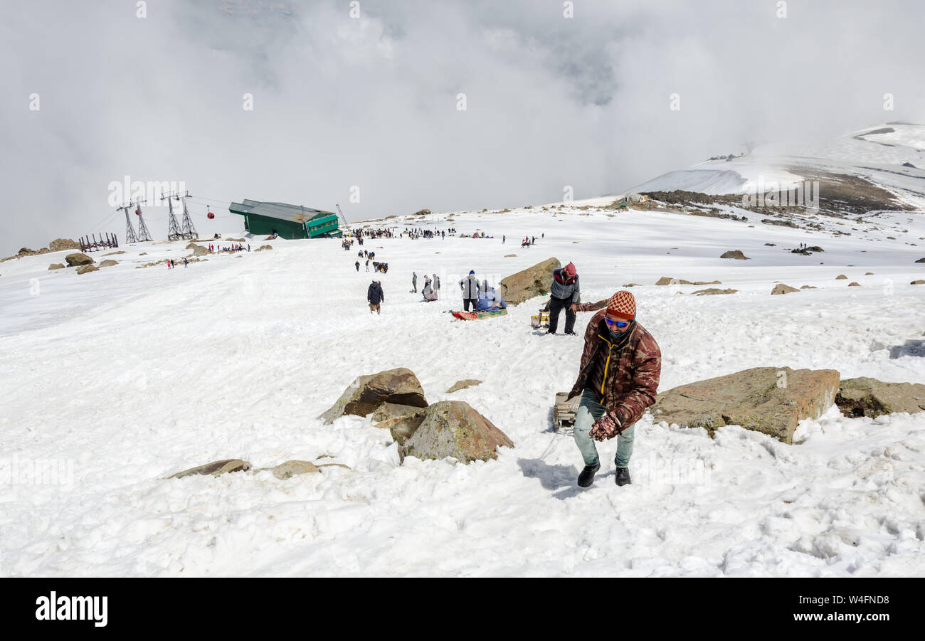 I turisti e gli estrattori di slittino arrampicata neve paesaggio riempito in Gondola Gulmarg Fase 2 / Apharwat picco, Gulmarg, Jammu e Kashmir India Foto Stock