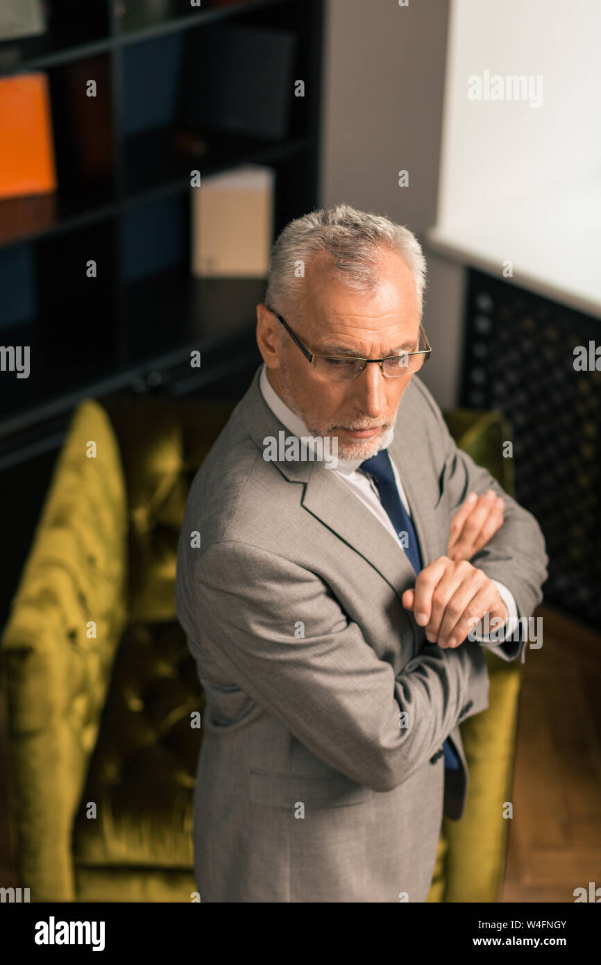 Guardare lontano. Considerato l'uomo in piedi con le sue mani incrociate nel suo ufficio vicino a una poltrona Foto Stock