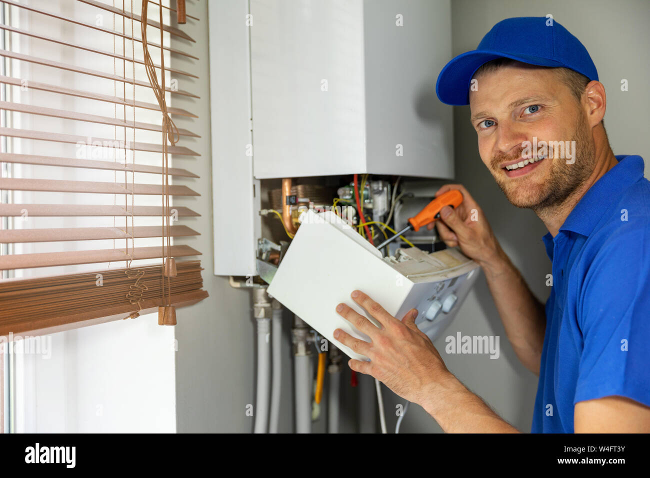 Manutenzione sorridente e servizio di riparazione ingegnere di lavoro con la casa del gas della caldaia di riscaldamento Foto Stock