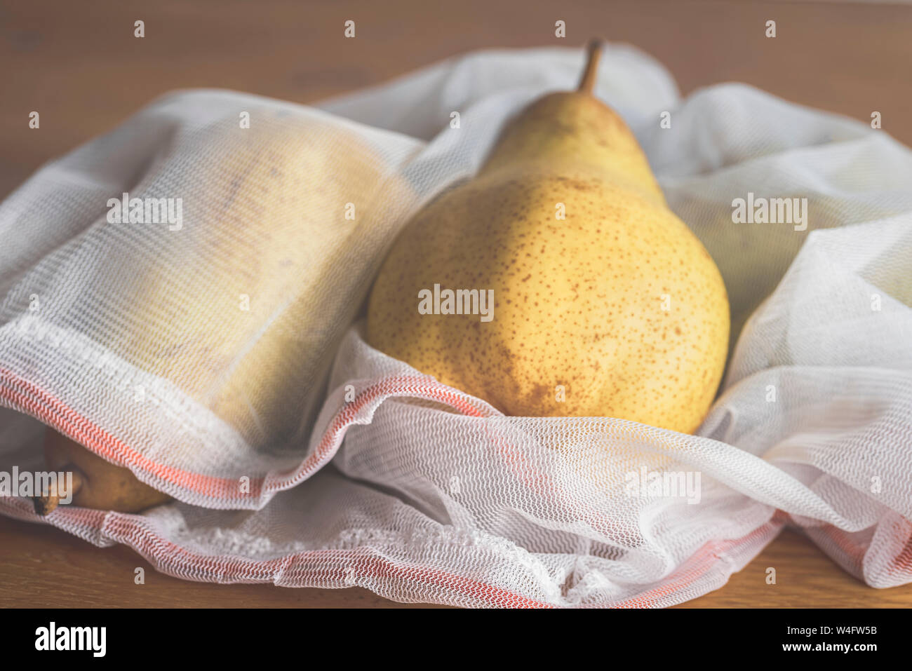 Stile di vita ecologico concetto con frutta fresca in riutilizzabili borse per lo shopping. Eco-friendly borsa a rete con pere in esso. Riduzione degli imballaggi in plastica concetto. Foto Stock