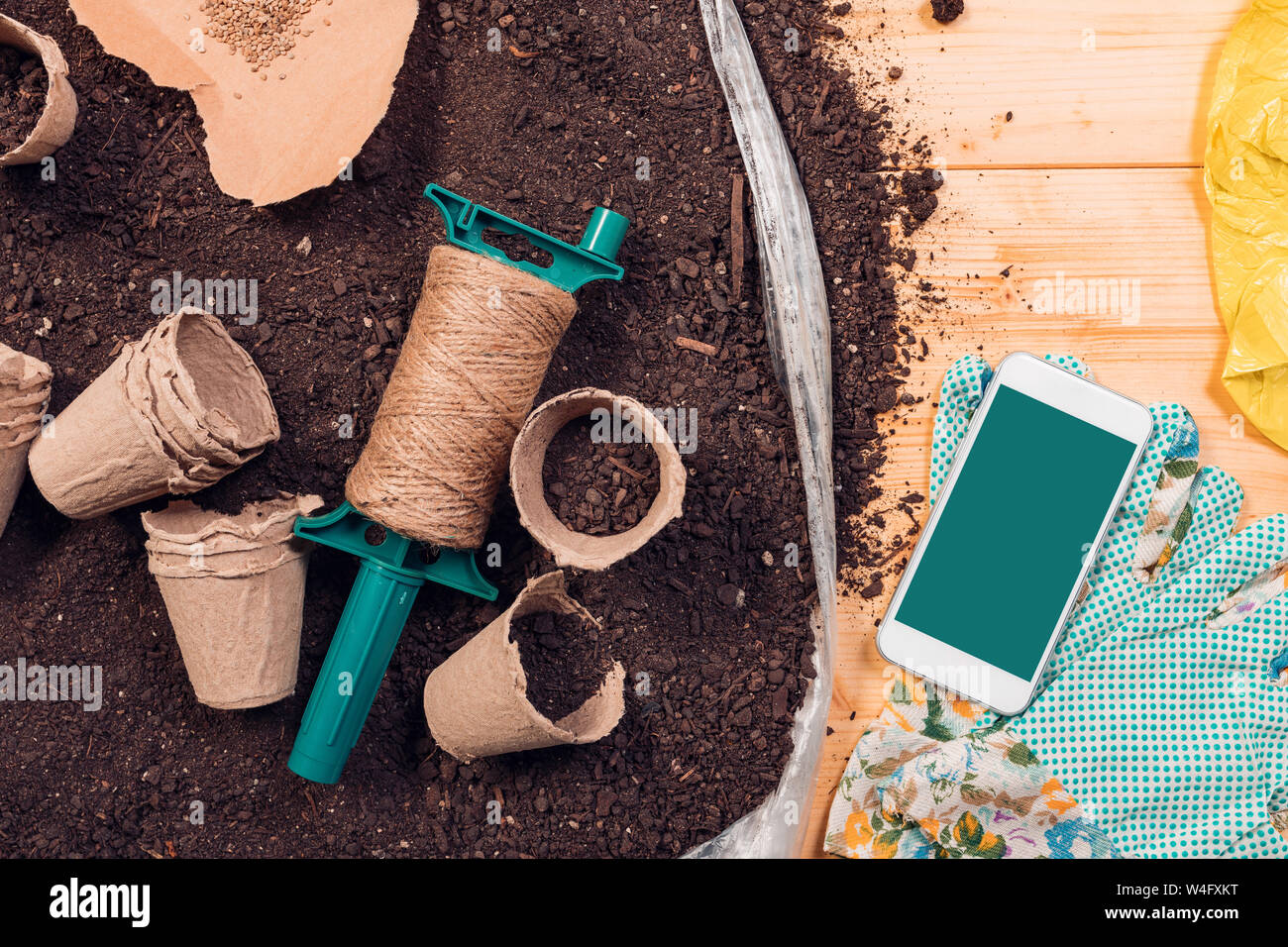 Lo schermo dello smartphone mock up per il giardinaggio e la semina app con gli strumenti e le attrezzature sul suolo di incapsulazione Foto Stock