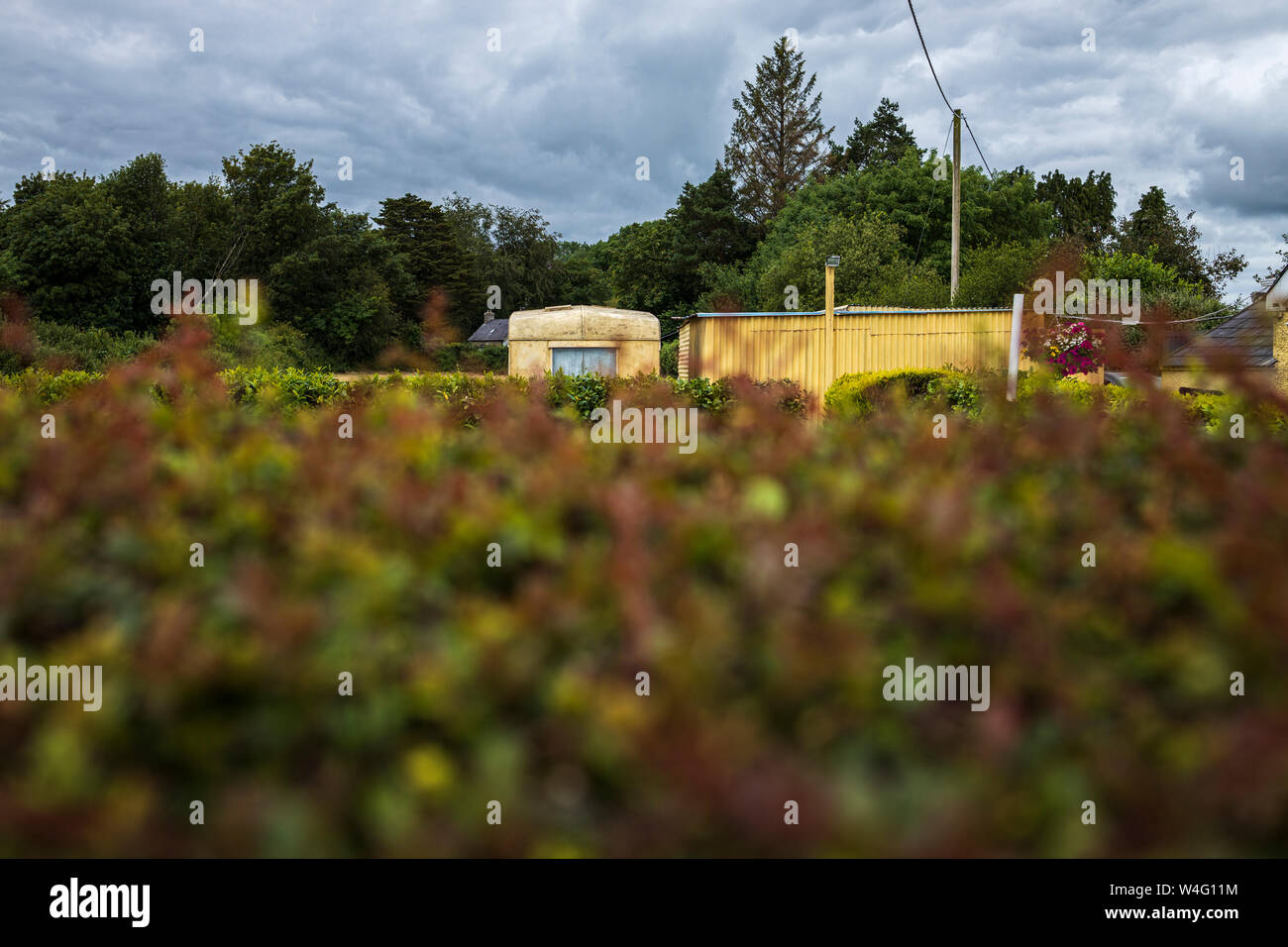 Roulotte parcheggiate in un giardino visto oltre una siepe, County Cork, Irlanda Foto Stock