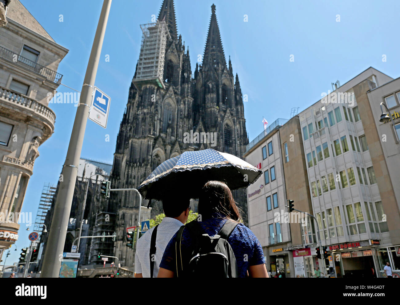 Colonia, Germania. 23 Luglio, 2019. I turisti stand con un ombrellone di fronte alla cattedrale. Secondo il tedesco servizio meteo, un record di onda di calore è che interessano la Germania e colpire il West particolarmente duri. Credito: Oliver Berg/dpa/Alamy Live News Foto Stock