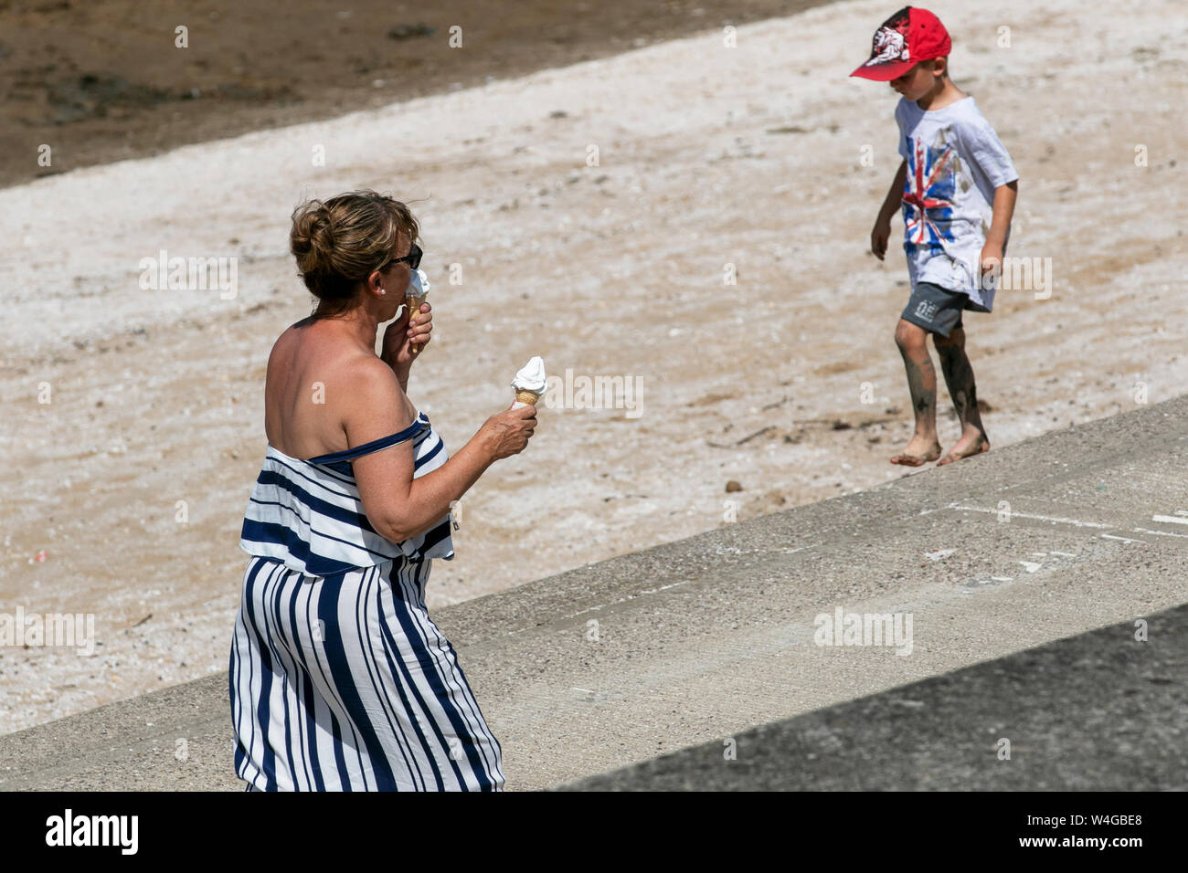 Southport, Merseyside. Regno Unito Meteo. 23 Luglio, 2017. 28C sul lungomare come passeggini in pantaloncini corti e cappello da sole godetevi una brezza sul resorts promenade Pier. Credito: MediaWorldImages/AlamyLiveNews Foto Stock