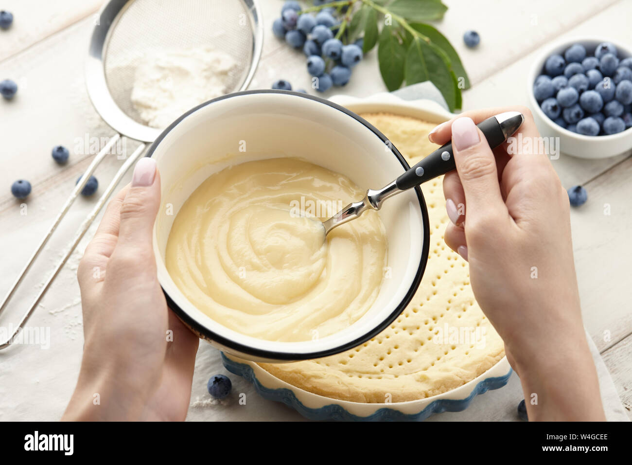 La donna la preparazione di panna montata per la torta ai mirtilli con frutti di bosco freschi. Crostata di mirtilli ricette di cucina. Foto Stock