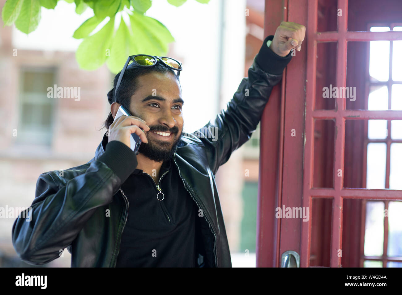 Ritratto di giovane sorridente uomo sul telefono esterno Foto Stock