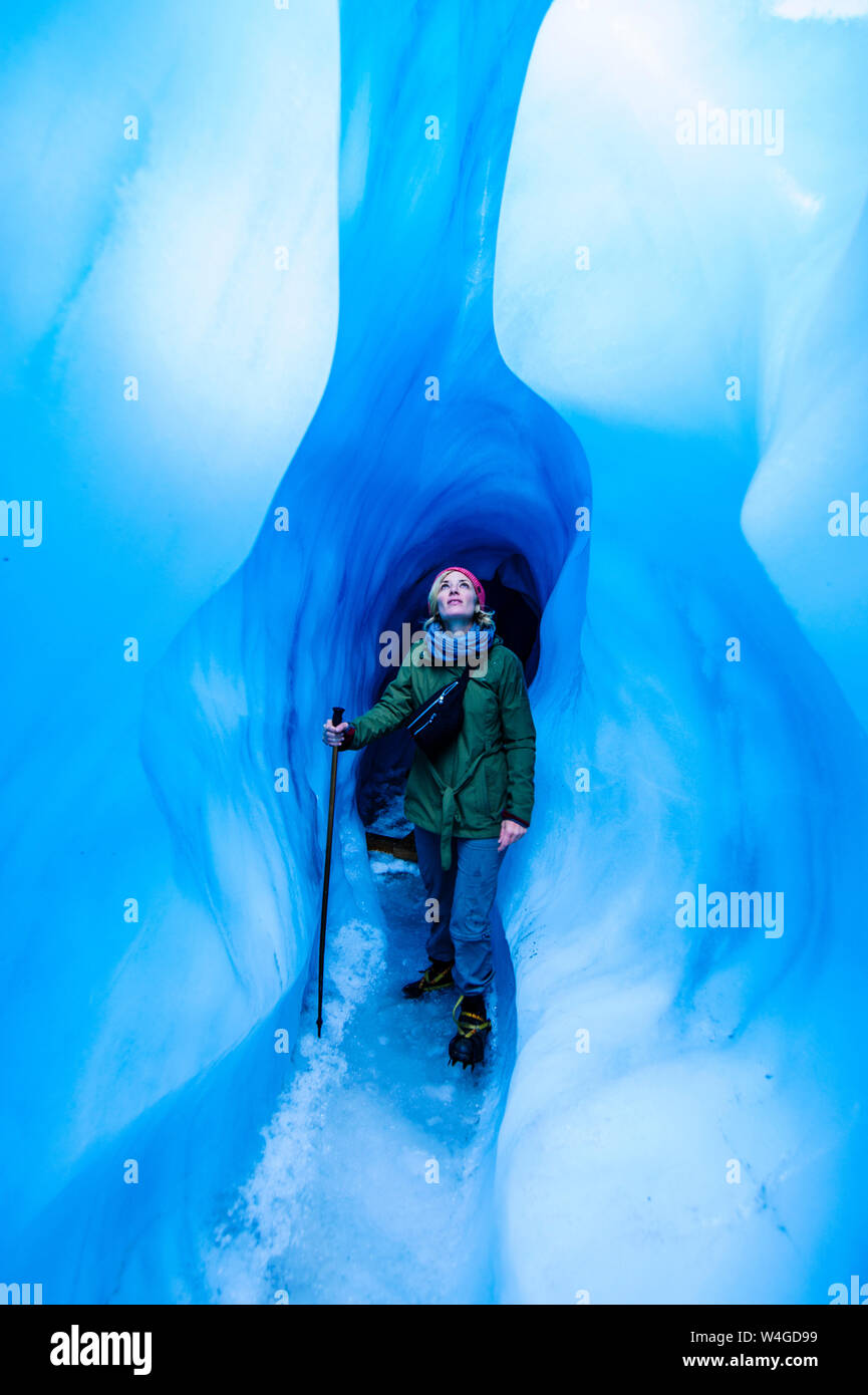 Donna in piedi in una caverna di ghiaccio, Fox Glacier, Isola del Sud, Nuova Zelanda Foto Stock