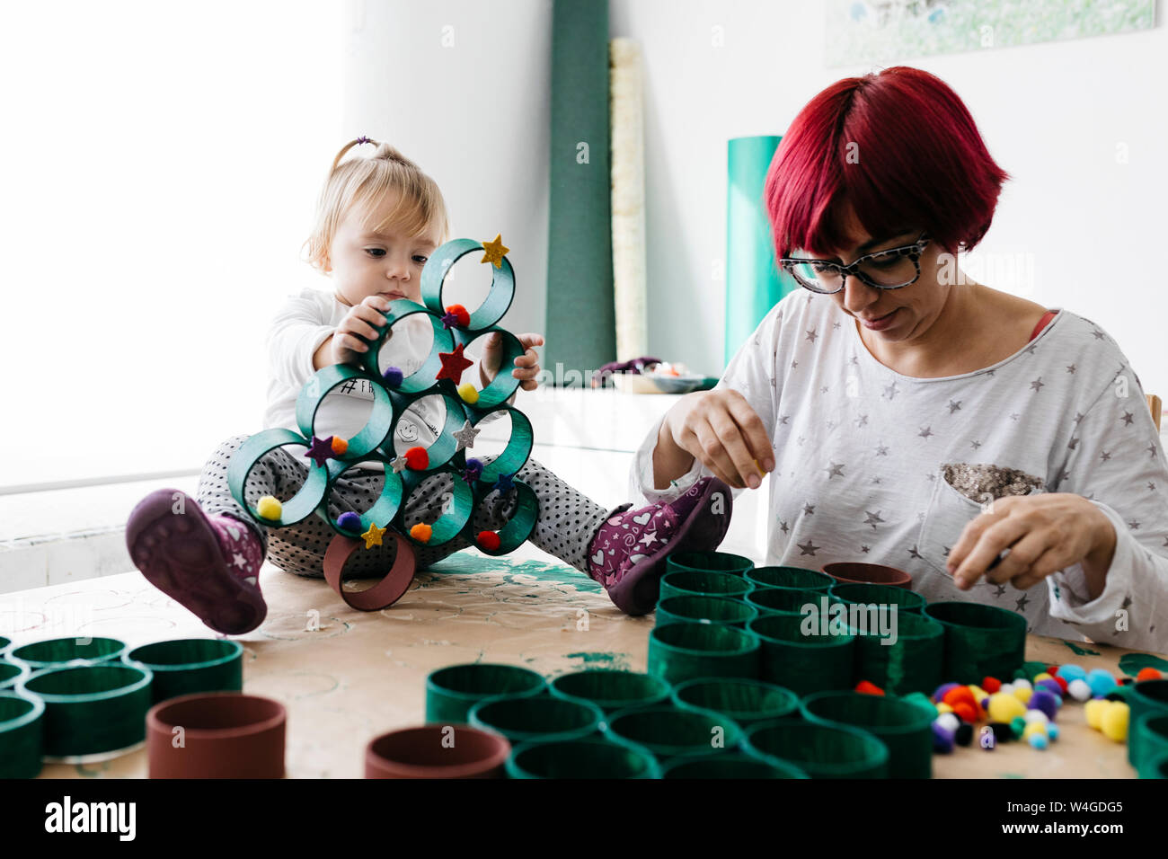 Madre e figlia fare artigianato a casa con accessori per fare un albero di Natale Foto Stock