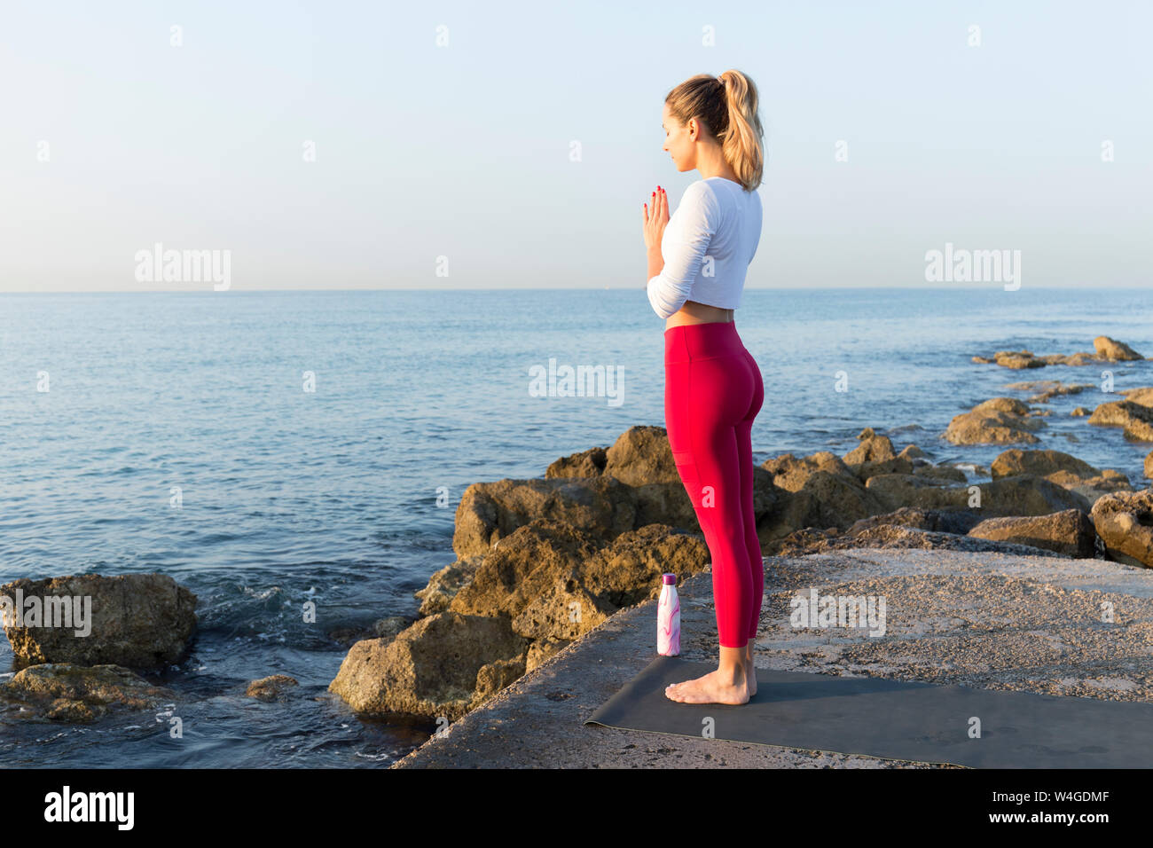 Giovane donna a praticare yoga sulla spiaggia, facendo la posizione di preghiera Foto Stock