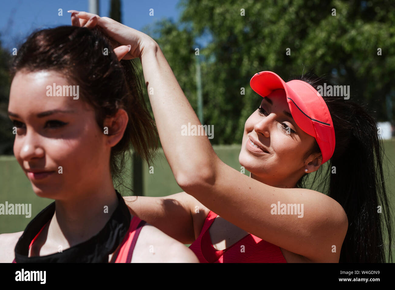 Donna sorridente giocatore di tennis facendo i capelli del suo partner di formazione Foto Stock