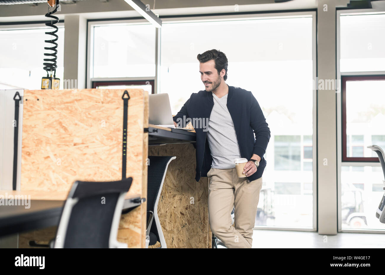 Giovane imprenditore in un ufficio moderno, utilizzando laptop sulla scrivania alta Foto Stock
