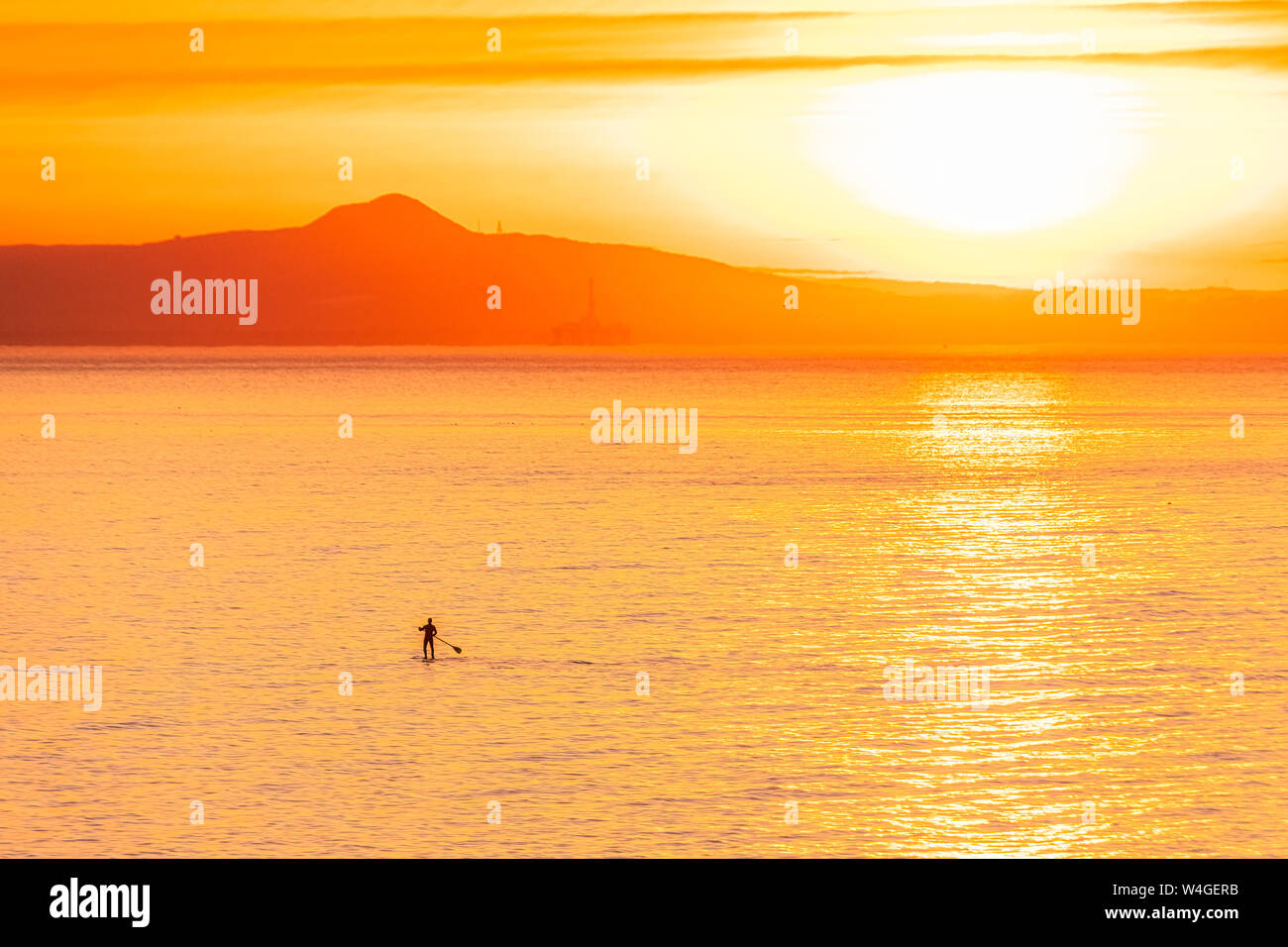 Uomo in stand up paddle board al tramonto, North Berwick, East Lothian, Scozia Foto Stock