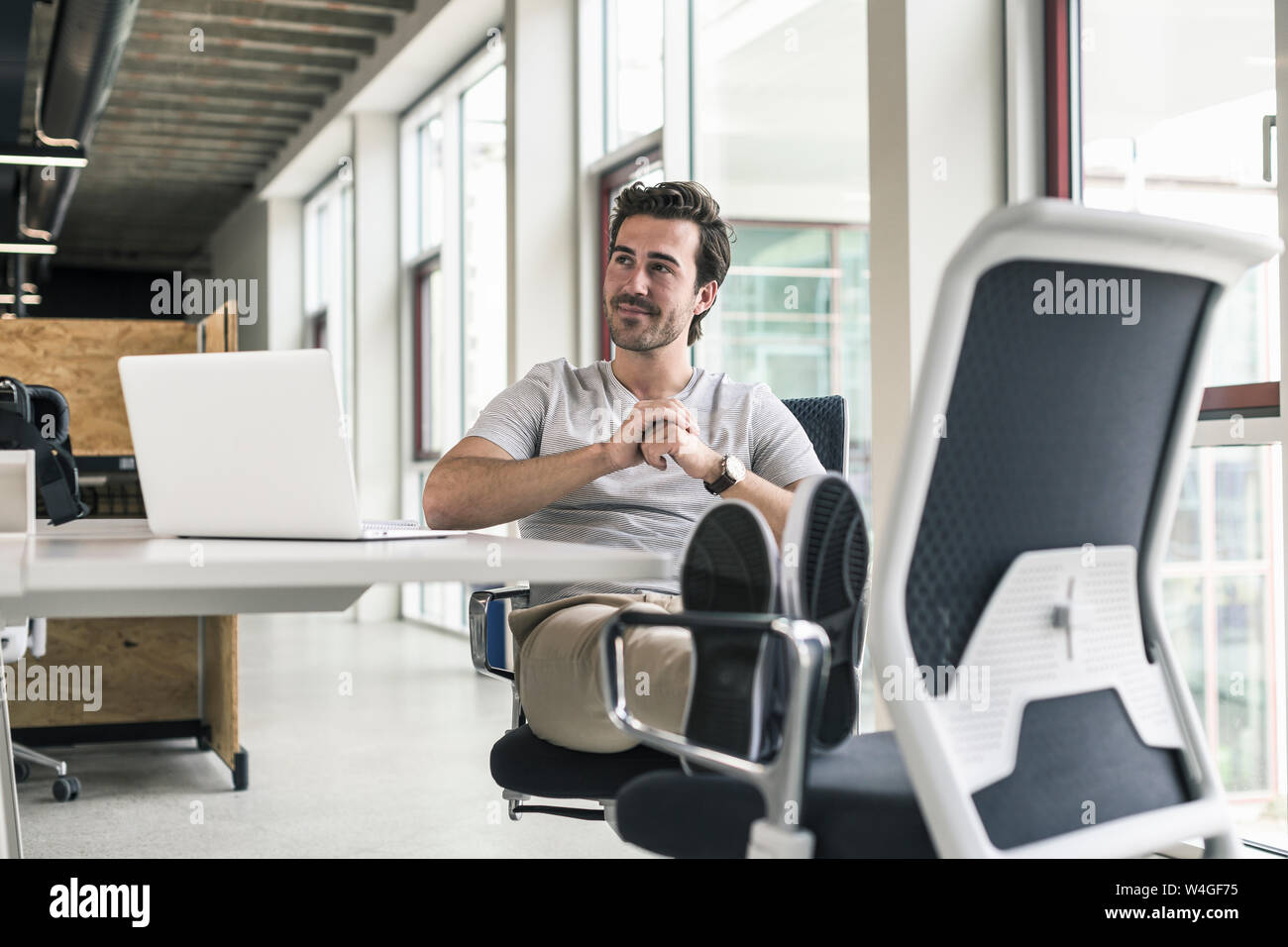 Giovane imprenditore lavora rilassato in un ufficio moderno, pensando Foto Stock