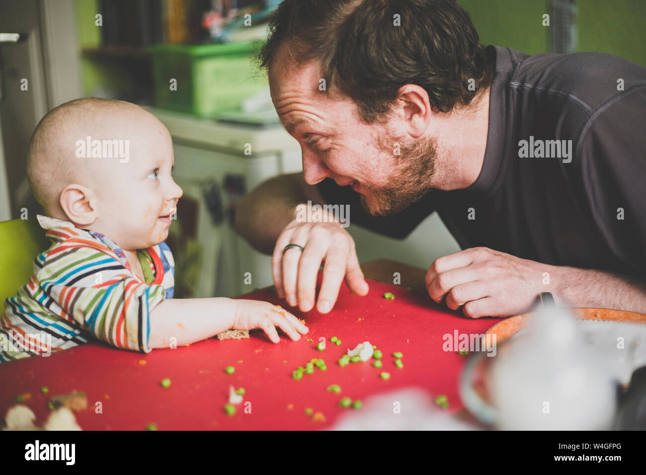 Padre alimentando il suo Figlio bambino con piselli verdi Foto Stock