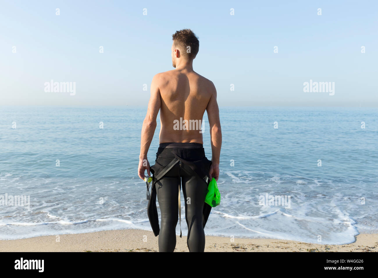Vista posteriore del giovane atleta sulla spiaggia, preparazione di nuotare Foto Stock