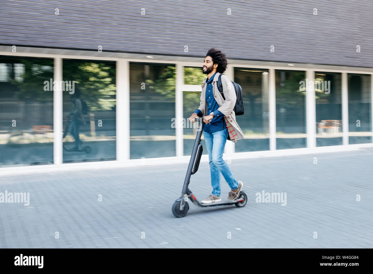 Uomo con zaino veloce di equitazione con la sua e-scooter in città Foto Stock