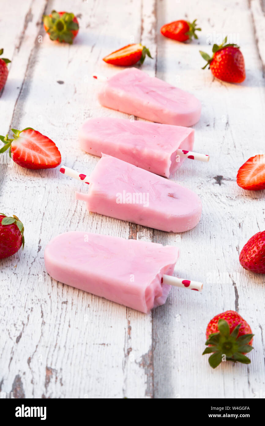 In casa di yogurt alla fragola ghiaccioli con fragole fresche in legno bianco Foto Stock