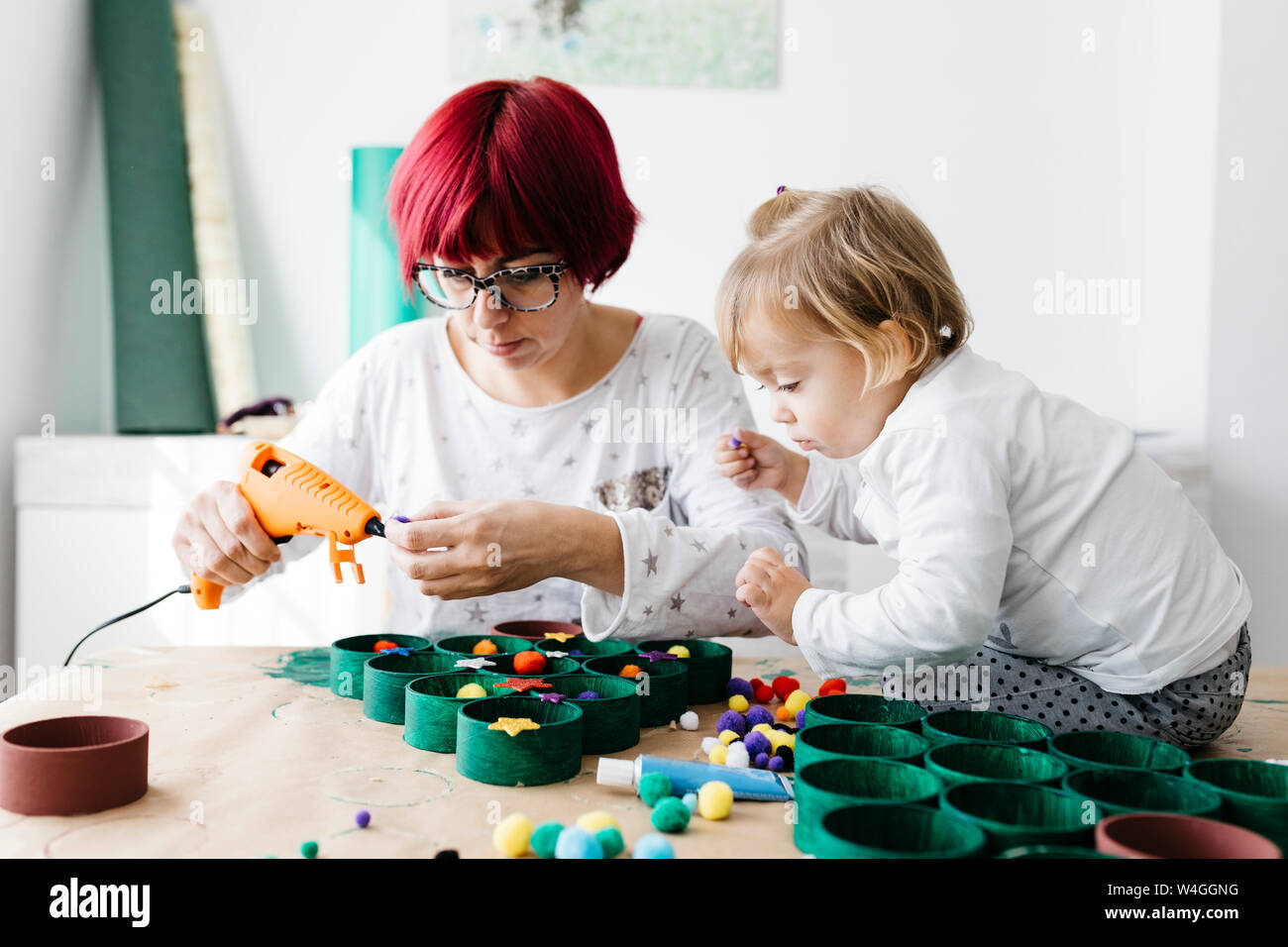 Madre e figlia fare artigianato a casa con accessori per fare un albero di Natale Foto Stock