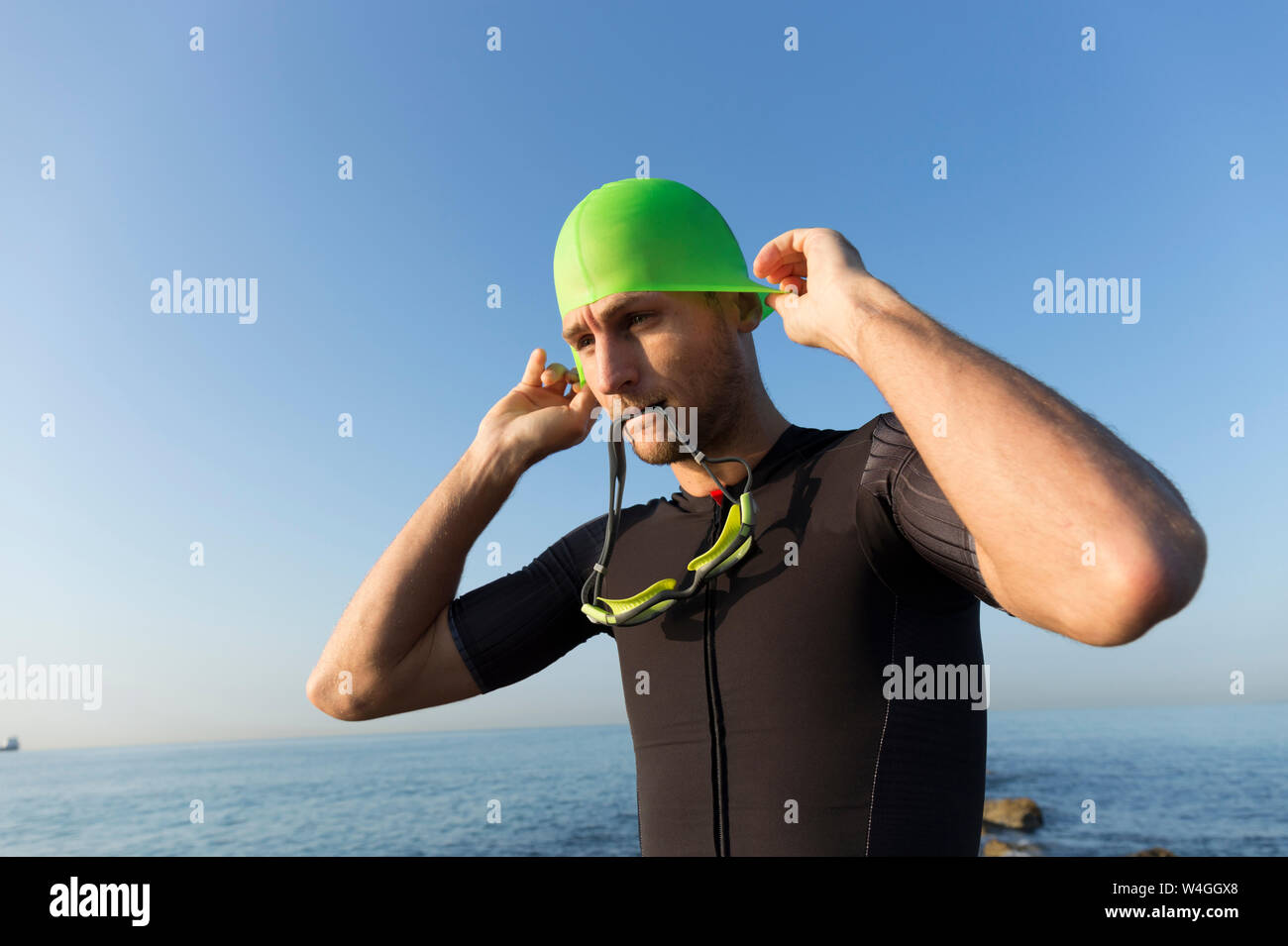 Triatleta preparando a nuotare, mettendo sulla cuffia per la piscina e gli occhiali di protezione Foto Stock