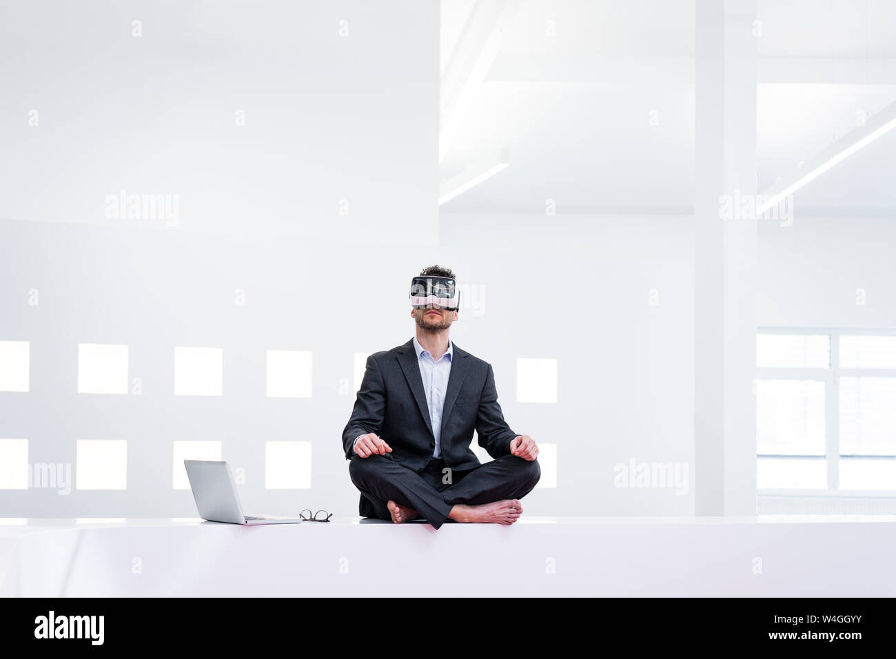 Imprenditore indossando occhiali VR in office accanto al laptop Foto Stock
